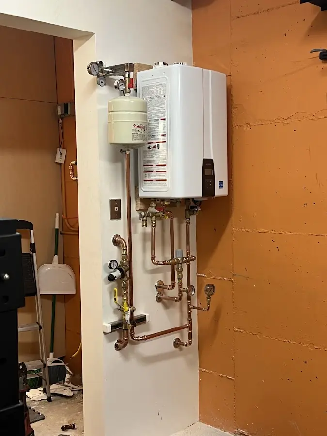 Plumbing technician inspecting water heater connections in South Kingstown